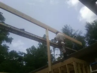 Carpenter setting a ridge beam over a new addition frame — Ice Dam Removal by Roofing Brothers in Rice
