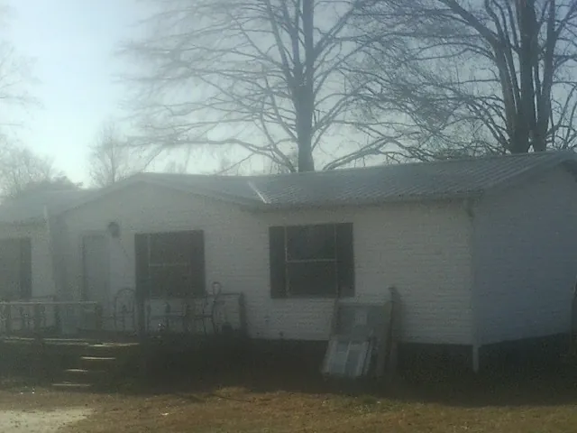 New metal roof on a white painted brick home on a foggy morning in Rice