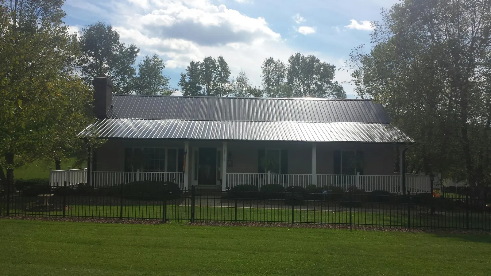 Gray metal roof on a brick ranch with a full width front porch — Gutter Guard Installation work by our crew in Rice