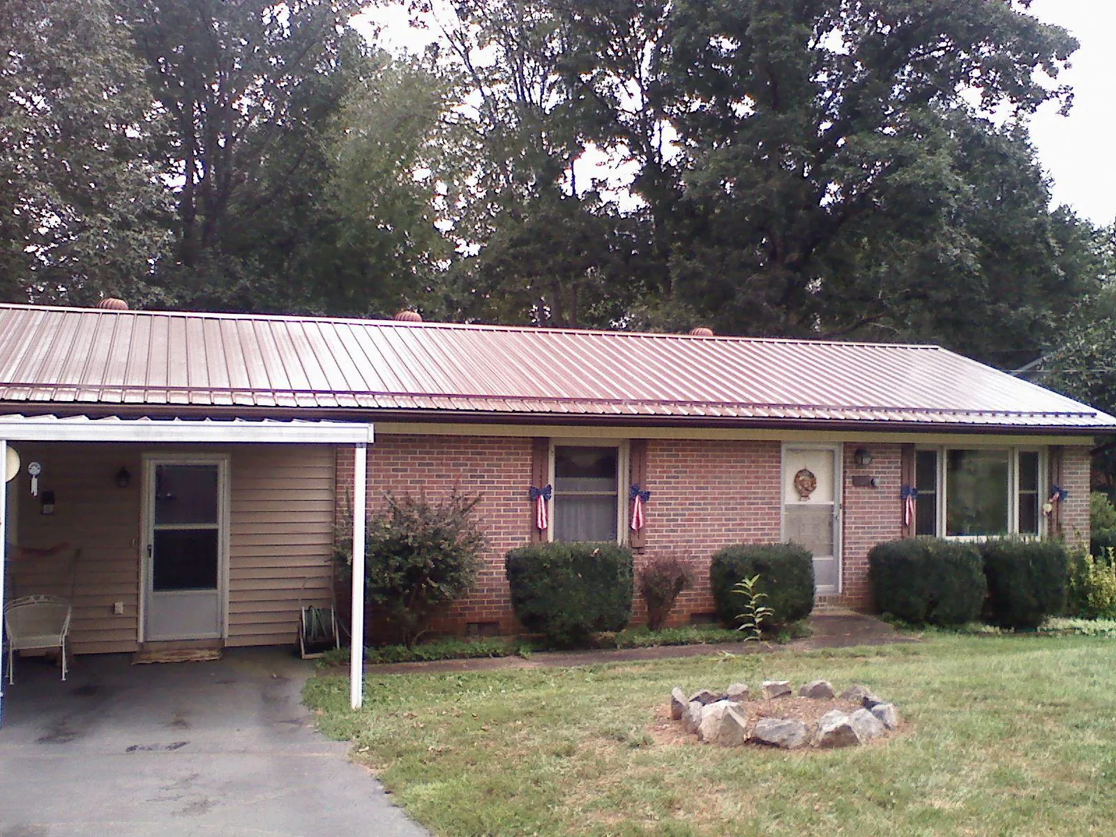 Bronze metal roof and carport on a brick ranch home — Roof Repair work by our crew in Rice